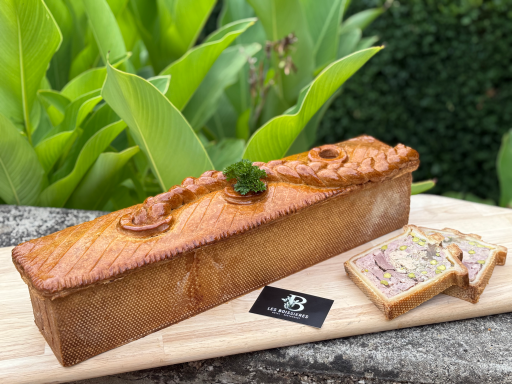 Pain de viande doré, décoré de persil, avec une tranche à côté sur une planche en bois.
